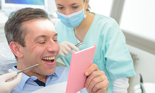 A man looking at a dentist's note after receiving Dental Bridge Care. 